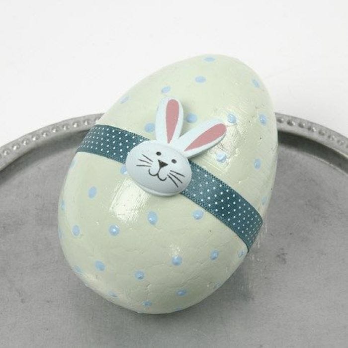 Pastel gekleurd ei met lint en houten figuur