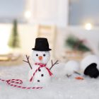 De kerstkabouter bouwt een sneeuwpop voor zijn deur