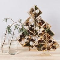 Geometrische kerstboom gedecoreerd met dennenappels, takken en licht